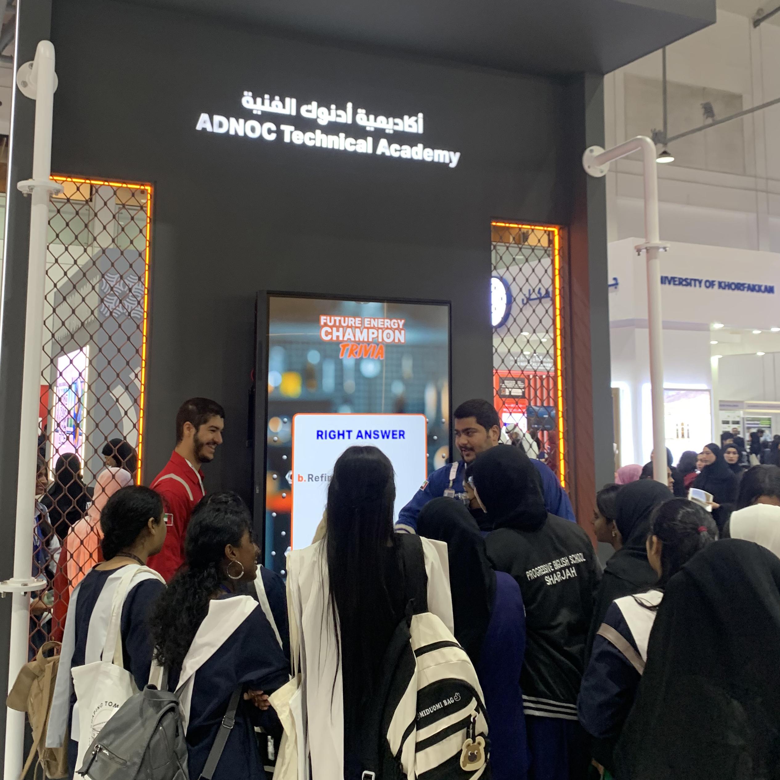 Students and guests play the Plinko Trivia Challenge at the ADNOC Technical Academy booth during a busy Dubai event